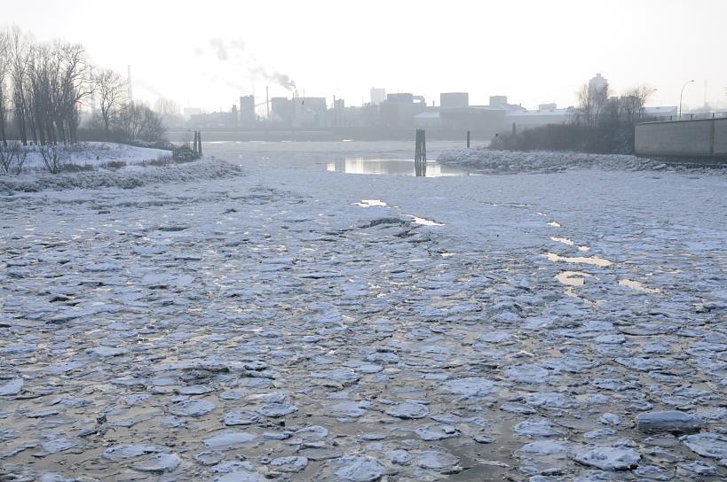 01129_5249 Winter in Hamburg - Eisschollen auf der Elbe. Blick ber Einfahrt zum Billehafen / Oberhafenkanal zur Norderelbe - lks. die kahlen Bume vom Elbpark Entenwerder. Am gegenber liegenden Elbufer im Dunst die Industrie auf der Veddel.