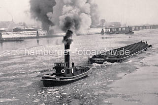 01141_33_18 Historisches Foto von der Norderelbe im Winter - Eisschollen treiben auf dem Wasser, ein Schlepper unter Dampf zieht einen Oberlnder Kahn. Im Hintergrund die Zollstation Entenwerder - niedrige Lagerhuser am Zollhafen, dahinter Wohnblocks von Hamburg Rothenburgsort.