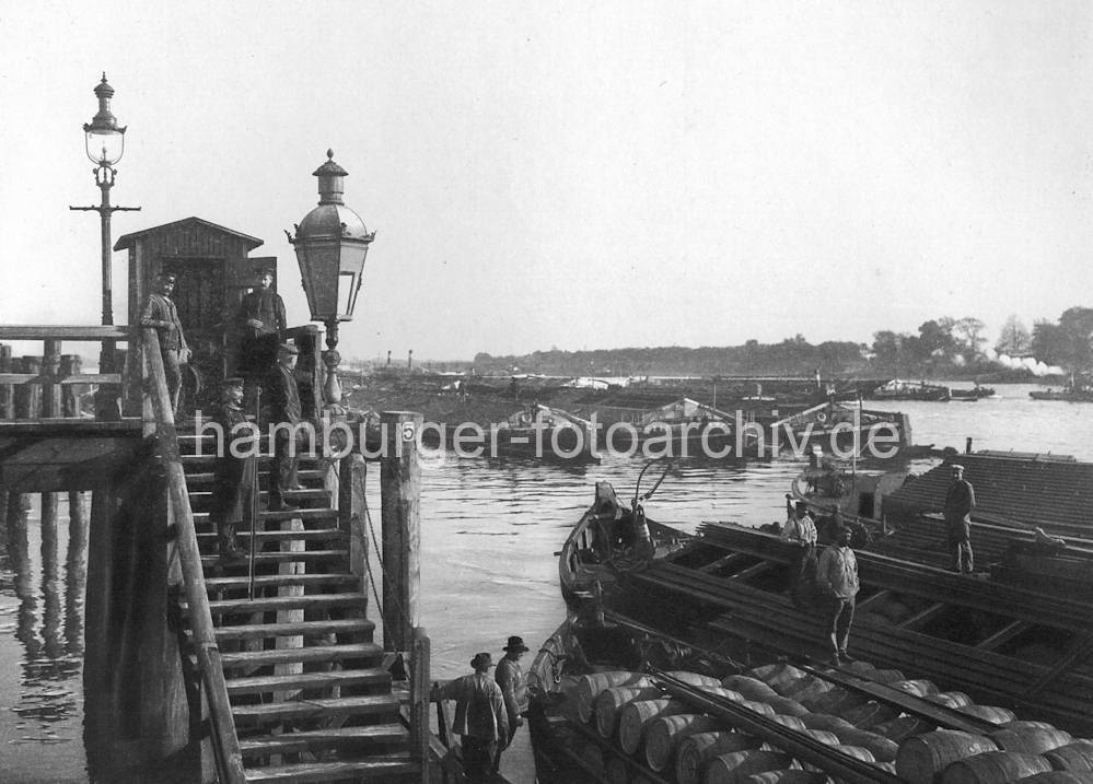 01144_45346 Zollstation Entenwerder in Hamburg Rothenburgsort an der Norderelbe - Binnenschiffe liegen in Paketen auf der Elbe; im Vordergrund stehen die Schiffer auf ihren Booten. Der Elblnder Kahn im Vordergrund hat Holzfsser geladen. Auf der Holztreppe stehen Zllner und Schiffer mit Peekhaken / Bootshaken.