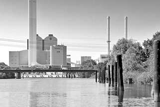 5740 Moorfleeter Kanal in Hamburg Billbrook; rostige Dalben am Kanalufer - im Hintergrund das Kraftwerk Tiefstack mit Schornsteinen.