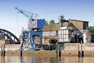 6381 Baustoffhandlung am Billehafen in Hamburg Rothenburgsort; Kran am Kai - Grafitti, im Hintergrund die Billhorner Brckenstrasse ber den Oberhafenkanal.