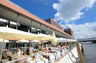 0430 Neubauten in der Hamburger Hafencity - Elbarkaden am Magdeburger Hafen / Aussengastronomie mit Sonnenschirmen am Wasser.