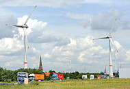 5206 Gewerbegebiet Hamburg Altenwerder, geparkte Lastkraftwagen mit Containern beladen - Windkraftanlagen mit riesigen Rotorblttern - dazwischen der Kirchturm der St. Gertrudkirche.