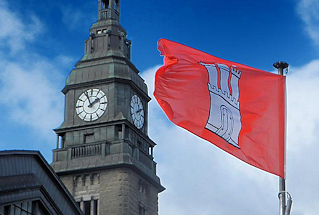 0170 Turm mit Kupferhelm mit Uhr - Hauptbahnhof Hamburgs - im Wind flatternde Fahne der Hansestadt.