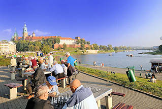 0078 Schachspieler im Freien in der Sonne am Ufer der Weichsel - Wisla; im Hintergrund der Wawel; Burg - Residenzschloss und Trme der Kathedrale in Krakau / Krakw.