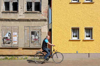 9441 Restauriertes Wohnhaus mit gelb gestrichener Fassade, verfallenes Gebude mit abbrckelndem Putz und Luken verschlossene Fenster - Fahrradfahrer; Architekturbilder aus Barth  / Alt + Neu.