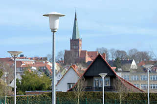 9852 Laternen / Lampen auf einem Parkplatz in Bergen - im Hintergrund der Kirchturm der St. Marien-Kirche in Bergen auf Rgen.