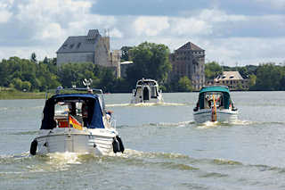 1532 Motorboote berqueren den Rblinsee und folgen dem Lauf der Havel in Frstenberg; im Hintergrund Industriegebude einer verlassenen Fabrik am Seeufer.