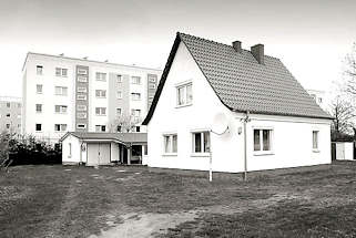 4118 Einzelhaus - Baustil der 1950er Jahre, Spitzdach - Garage; im Hintergrund mehrstckige Wohnhuser - Schwarz weiss Fotografie.