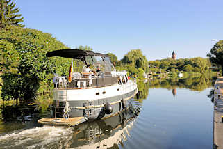 8794 Motorboot in Fahrt auf der Mritz - Elde - Wasserstrasse in Lbz; im Hintergrund der alte Wasserturm der Stadt.