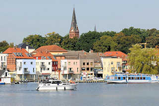 9226 Wohnhuser an der Hafenpromenade von Malchow am Malchower See - ein Ausflugsschiff legt ab; Kirchturm der Stadtkirche.