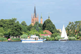 1694 Blick vom Wasser ber die Havel zur Heiligen Geist Kirche der Stadt Werder; ein Segelboot fhrt auf dem Fluss.