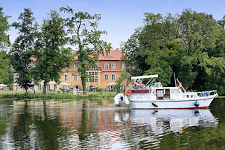 0730 Blick ber die Havel bei Zehdenick - ein Motorboot fhrt Richtung Schleuse; im Hintergrund das Havelschloss / Restaurant, Hotel.
